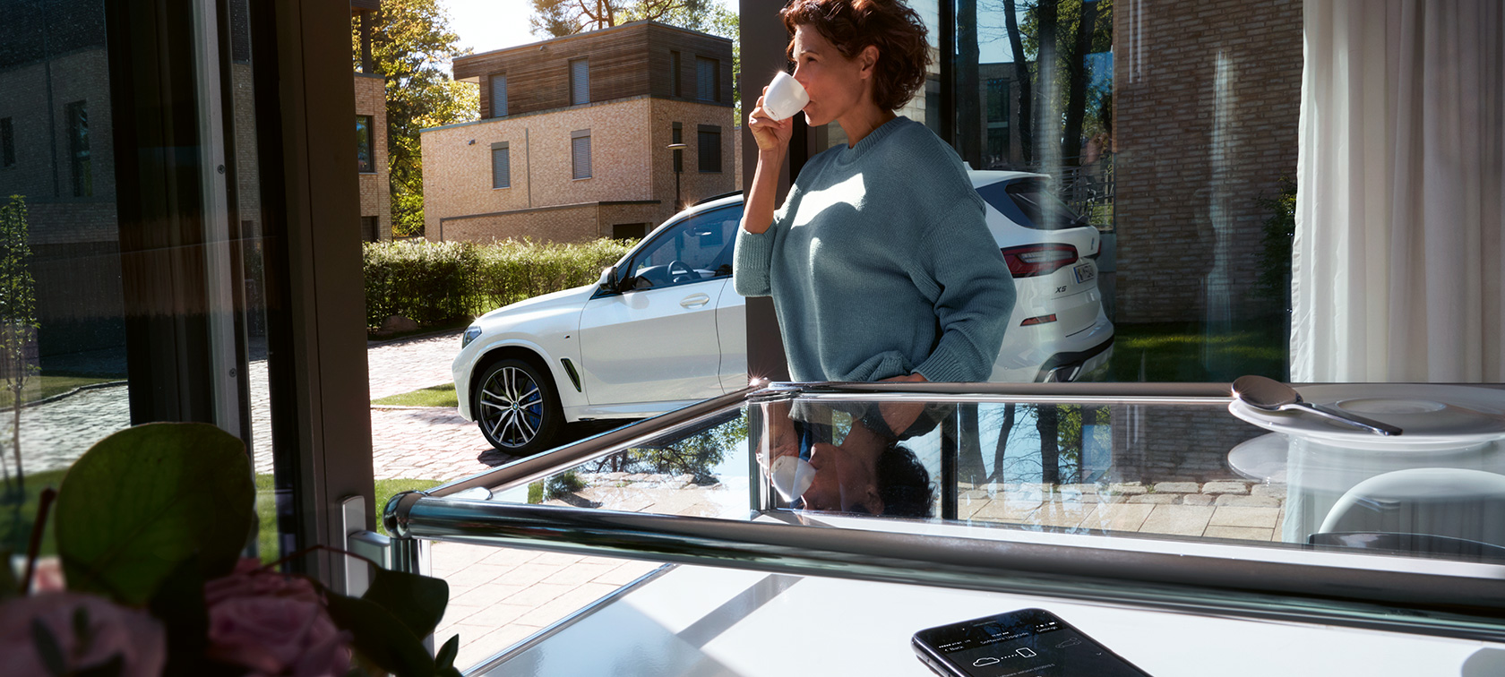 BMW Remote Software Upgrade Kvinna dricker ur en mugg under tiden som BMW Remote Software Upgrade uppdaterar programvaran i hennes BMW X5