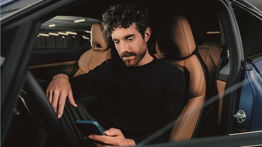 En man sitter i en BMW En man sitter i en BMW och tittar i sin smartphone