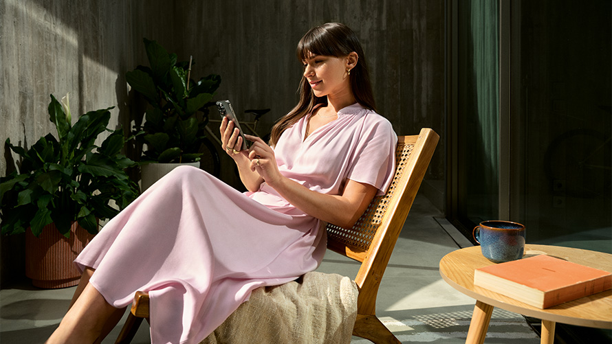 En kvinna i rosa klänning med en smartphone i handen Remote Inside View Remote Inside View en kvinna i rosa klänning med en smartphone i handen sitter på en stol
