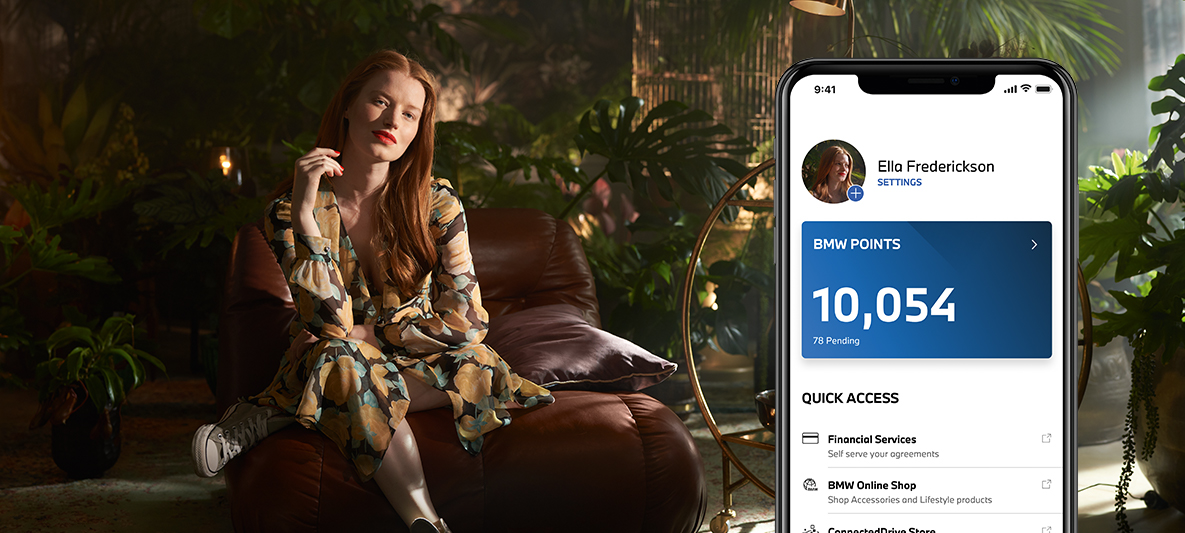 My BMW-appen kör elektriskt och samla BMW Points Kvinna sitter i fåtölj framför växter My BMW-appen kör elektriskt och samla BMW Points Kvinna sitter i fåtölj framför växter