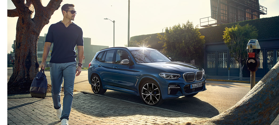 Man med solglasögon framför blå BMW Man med solglasögon framför blå BMW
