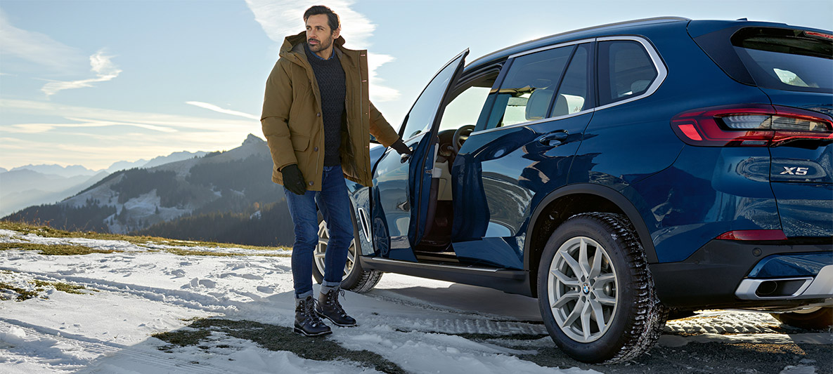 Man i snö framför blå BMW X5 Man i snö framför blå BMW X5