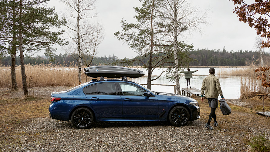 BMW med takbox parkerad framför en sjö. BMW med takbox parkerad framför en sjö.