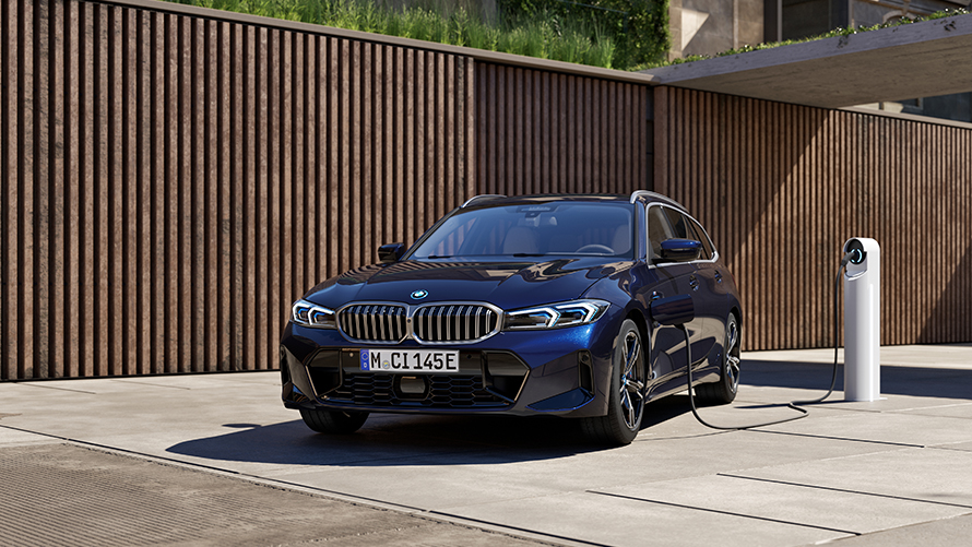 En mörkblå BMW 3-serie Touring laddhybrid som laddas vid en laddstolpe