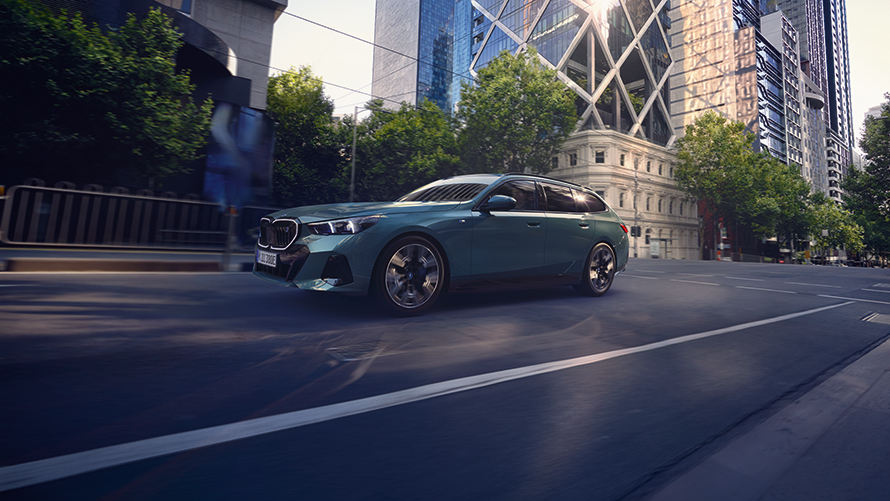 En blå BMW 5-serie Touring sedd från sidan körandes på en väg