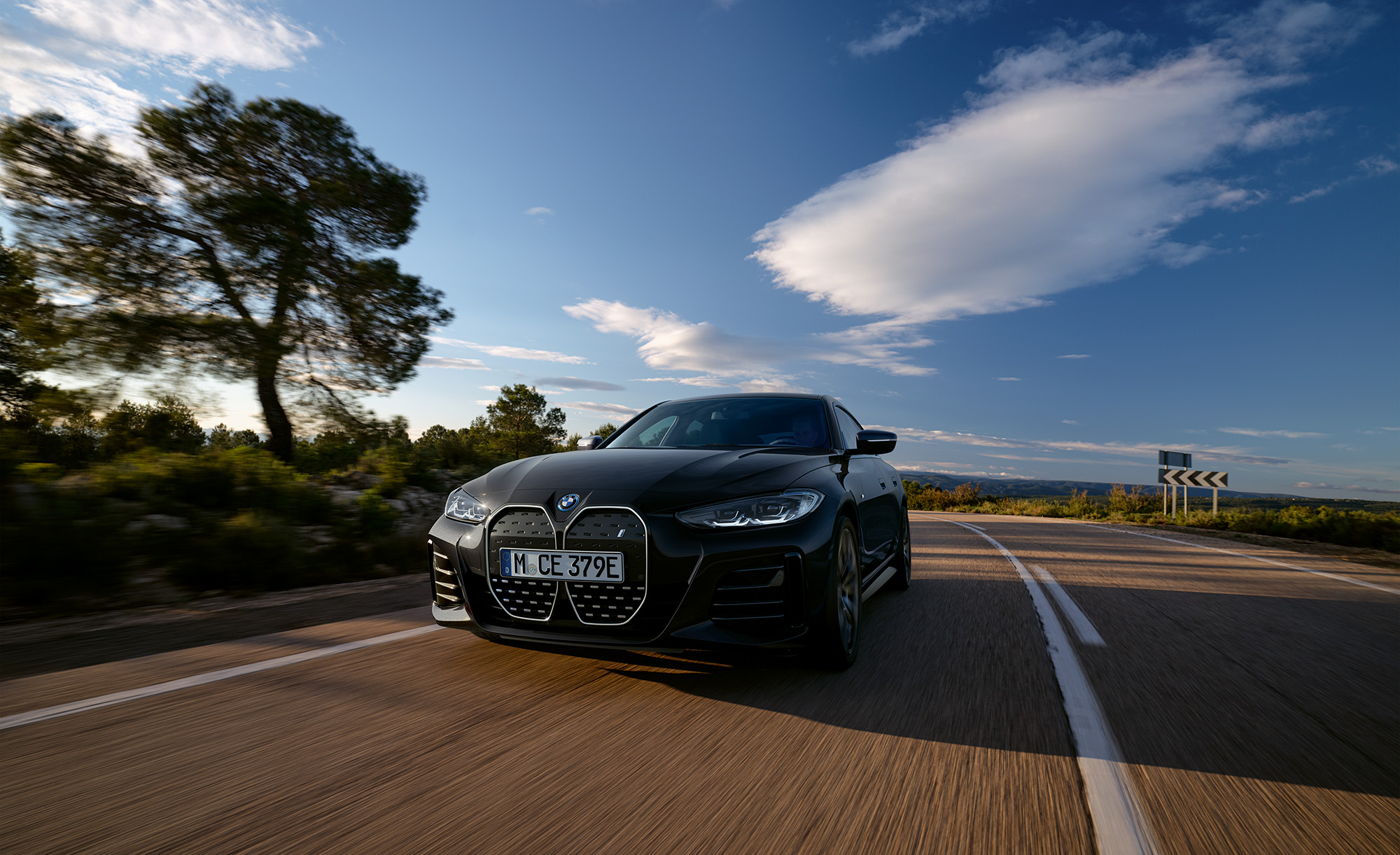 En svart BMW i4 sedd framifrån körandes på en landsväg