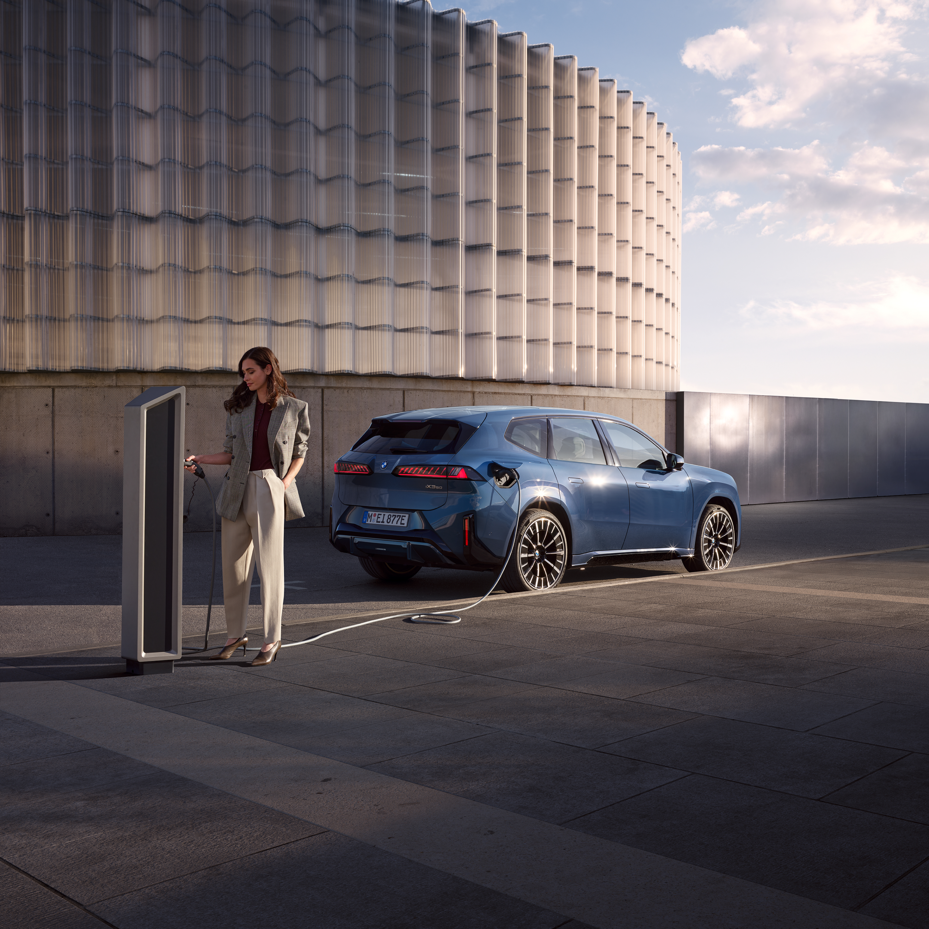 En man står bredvid en BMW iX3, som är ansluten till en publik laddstation