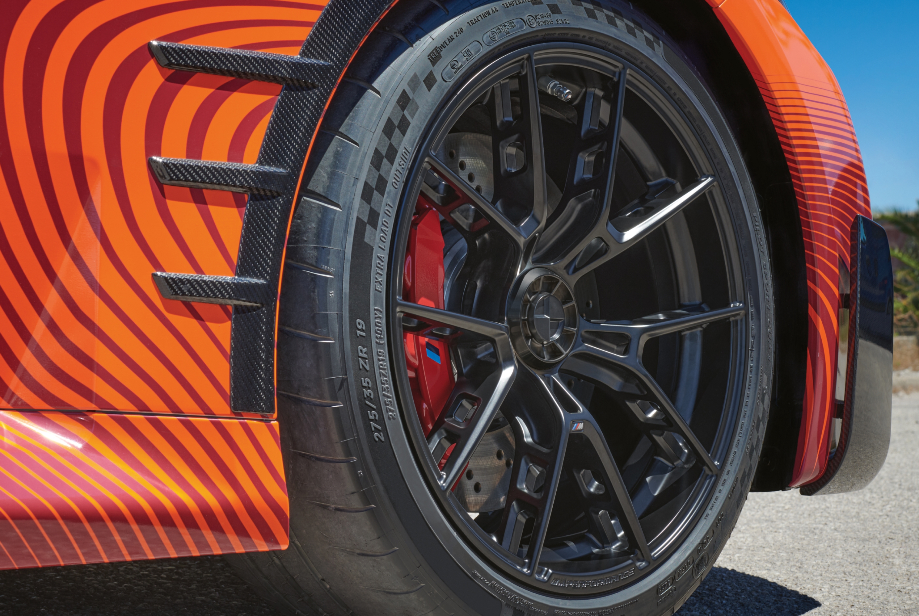 BMW på en grusväg framför en sjö – detaljerad bild av hela sommarhjulet 21" M Performance-lättmetallfälg krysseker 943 M Frozen Midnight Grey